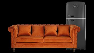A couch next to a fridge.