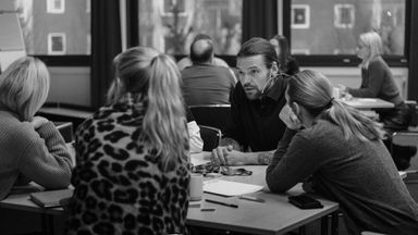 Kursdeltagare som sitter runt ett bord och diskuterar engagerat.