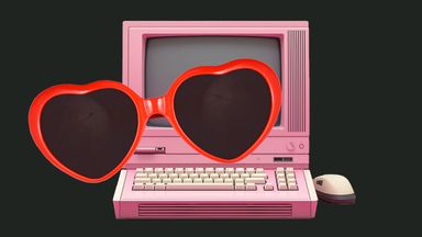Heart-shaped sunglasses in front of a pink, old school computer